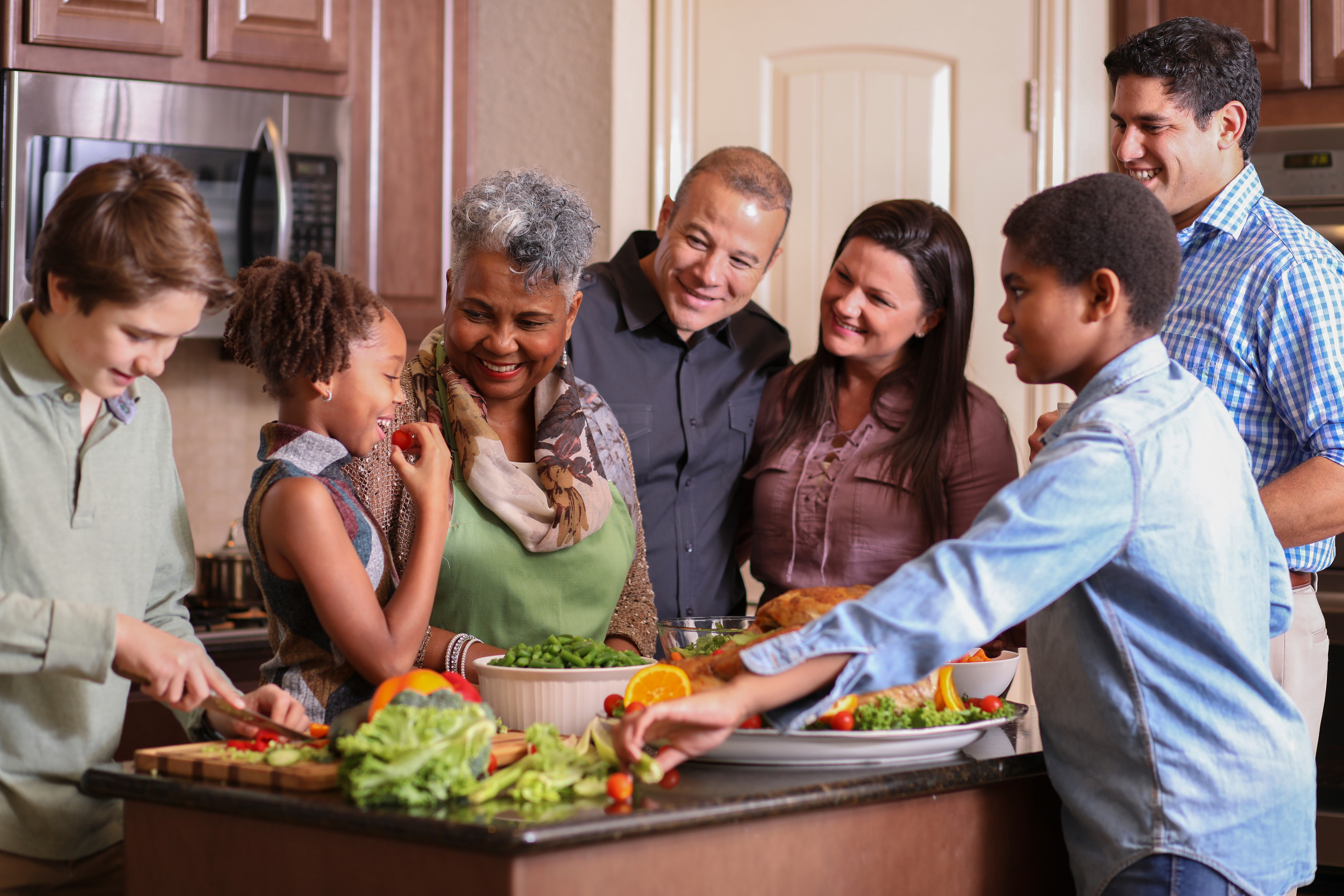 Diverse family in home kitchen cooking Thanksgiving dinner.